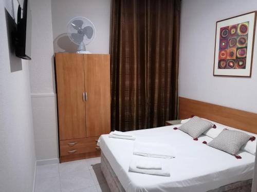 a bedroom with two beds and a cabinet with a fan at Pensión A&E in Manises