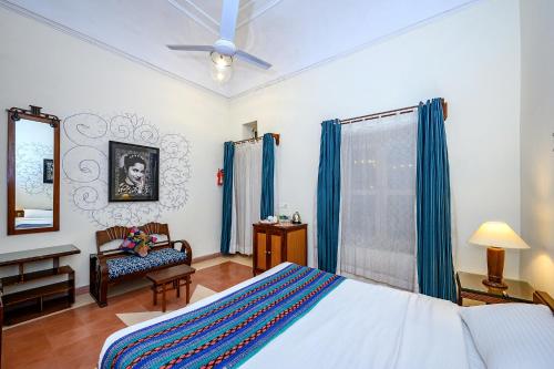 a bedroom with a bed and a chair and a mirror at Neemrana's - Tijara Fort Palace in Alwar
