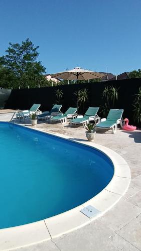 a blue swimming pool with lounge chairs and an umbrella at Casa Simone in Costinesti