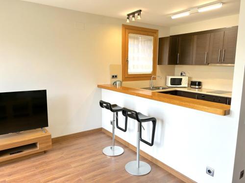 a kitchen with a counter and two bar stools at Apartament al centre d'Esterri amb vistes úniques by RURAL D'ÀNEU in Esterri d'Àneu