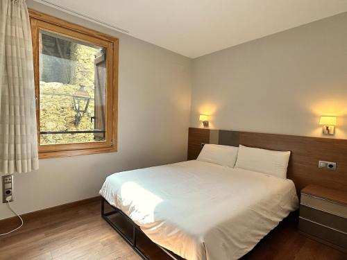 1 dormitorio con cama blanca y ventana en Apartament al centre d'Esterri amb vistes úniques by RURAL D'ÀNEU, en Esterri d'Àneu