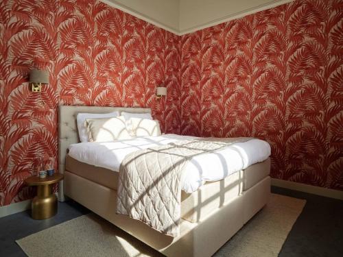 a bedroom with a bed with red wallpaper at Kerkhotel Bij De Pastorie in Reitsum