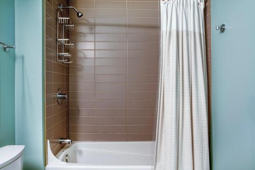 a bathroom with a white tub and a shower at Pioneer Square studio w gym bbq nr stadium SEA-586 in Seattle