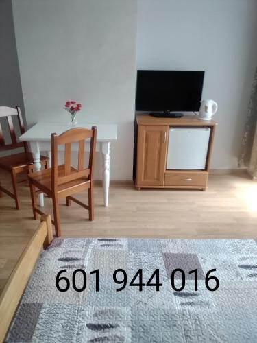 a living room with a tv and a table with a chair at Kwatery UMARIOLl in Władysławowo