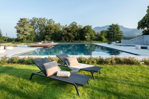 two lounge chairs on the grass next to a swimming pool at Palace Grand Hotel Varese in Varese