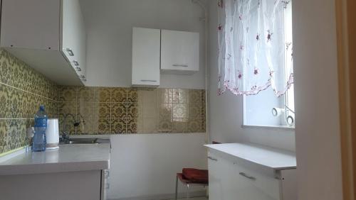 una cocina con armarios blancos y una ventana en A nicely furnished, cozy apartment located in the center of the city with complimentary Mongolian traditional meal upon your arrival en Ulán Bator