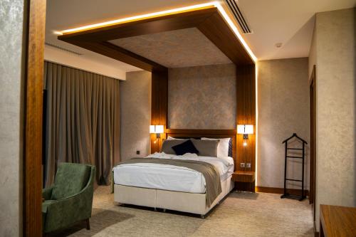 a bedroom with a large bed and a green chair at Parwar Hotel in Duhok