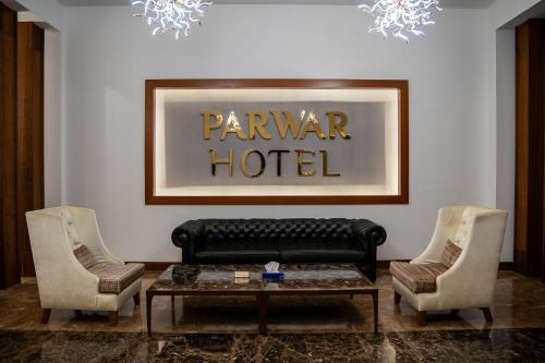 a living room with a black leather couch and two chairs at Parwar Hotel in Duhok