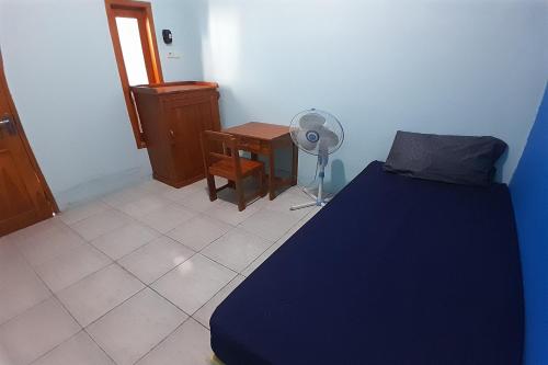a bedroom with a bed and a table and a fan at SPOT ON 92814 Gioba Kost Syariah in Grobogan