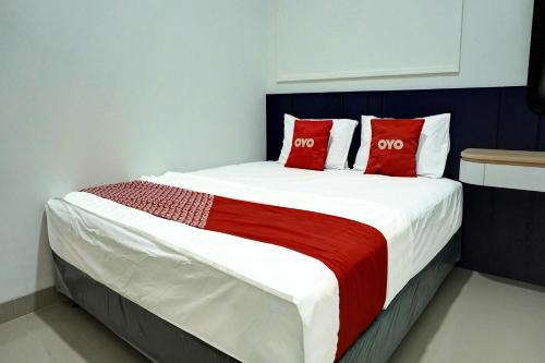 a bedroom with a large bed with red pillows at Capital O 92804 La Tansa Syariah Hotel in Cibeber