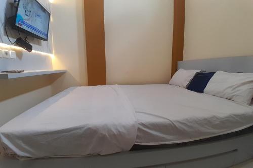 a bedroom with a white bed with a tv on the wall at OYO Life 92812 Galih Kostel 2 Syariah in Grobogan