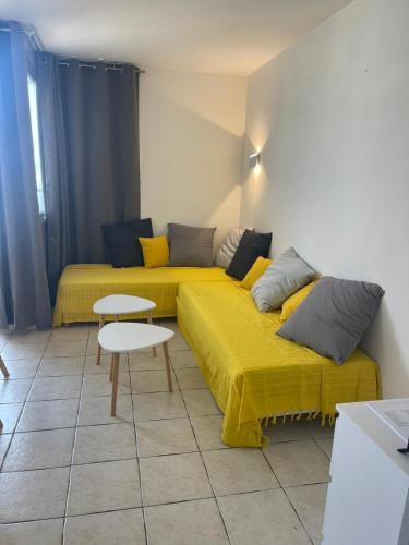 un salon avec deux lits avec des draps jaunes dans l'établissement Résidence Graziella studio 605, à Juan-les-Pins