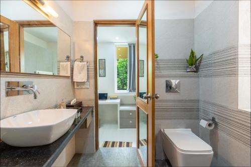 uma casa de banho com um lavatório branco e um WC. em Homlee-3bhk Green Luxury in SDEL em Nova Deli