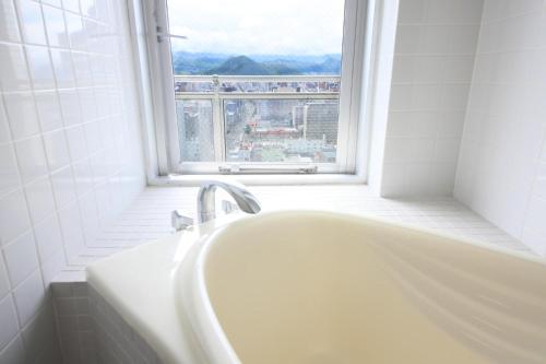 a white bath tub in a bathroom with a window at AMS TOWER 2101 in Sapporo