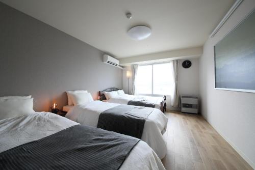 a hotel room with two beds and a flat screen tv at AMS TOWER 2101 in Sapporo