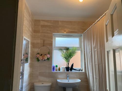 a bathroom with a sink and a toilet and a window at Berks Luxury serviced Apartments,5 Bedrooms, 5 double beds, 2 bathrooms, free super fast WiFi & parking in Earley