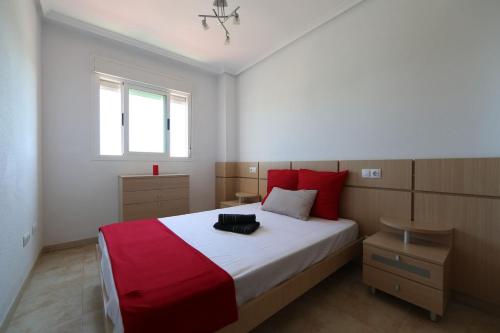 una camera da letto con un letto grande con cuscini rossi di Apartamento con vistas al mar y montaña a Oropesa del Mar