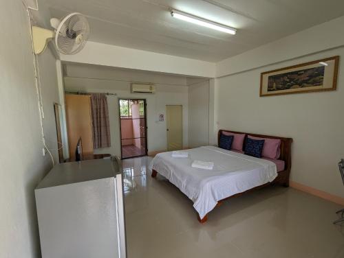 a bedroom with a bed and a fan at Alongkon Mansion in Sakon Nakhon