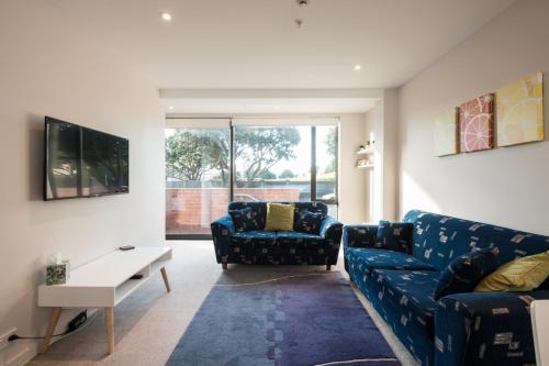 a living room with a blue couch and a table at Nouvo Apartments in Wellington