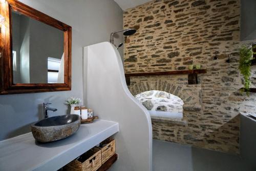 baño con lavabo y pared de piedra en Katrani studios, en Symi