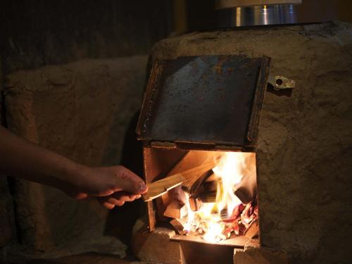 une personne met la main dans un four à briques dans l'établissement 能登ごはん農場 暮らしの宿じろざみ, à Nanao