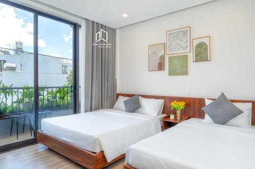 two beds in a room with a balcony at PLEIKU HIGHLANDS BOUTIQUE HOTEL in Plei Brel (2)