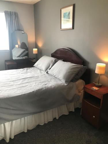 a bedroom with a bed and two lamps and a mirror at Park Cottage in Saint Marys