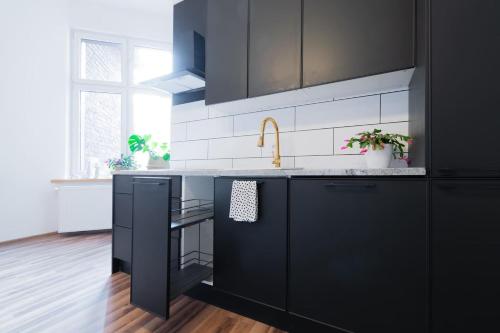 a kitchen with black cabinets and a sink at Opera in Bytom