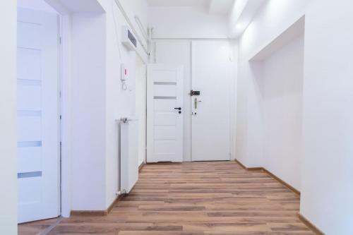 a hallway with white doors and a wooden floor at Opera in Bytom