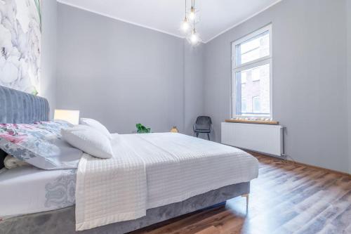 a white bedroom with a bed and a window at Opera in Bytom