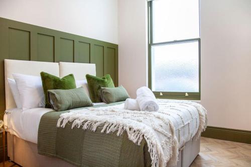 um quarto com uma cama grande e almofadas verdes e brancas em Prestige 2 Bedroom Apartment With Free Parking em Bournemouth