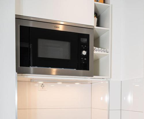 a microwave oven sitting on top of white cabinets at Cozy Apartment in Prime Location with Balcony - Hotel Comfort in 2 Room Apartment in Cologne Neumarkt - City Loft 11 - in Cologne