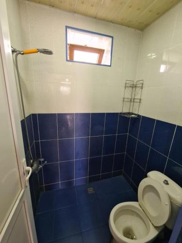 een blauw betegelde badkamer met een toilet en een raam bij Nasimi Villa in Gabala