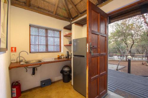 eine Küche mit einem Kühlschrank und einer Theke mit einem Fenster in der Unterkunft South Safari Lodge in Marloth Park