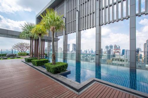 a swimming pool on the roof of a building with palm trees at Luxury 1Bed 1Bath 300m BTS Phrom Phong, Emporium EmSphere EmQuartier in Bangkok