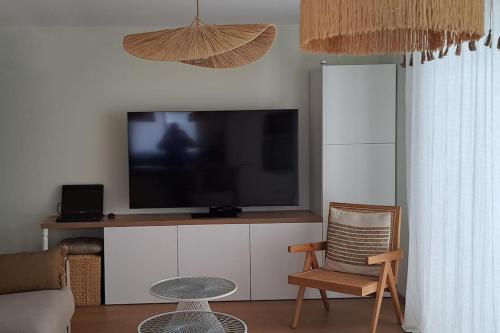 un salon avec une télévision et une chaise dans l'établissement Magnifique T2 - Les pieds dans l'eau piscine/plage, à Carry-le-Rouet