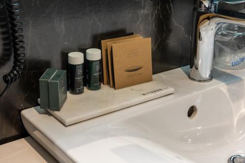 a bathroom sink with a box and three bottles on it at Hotel Constantine the Great in Belgrade