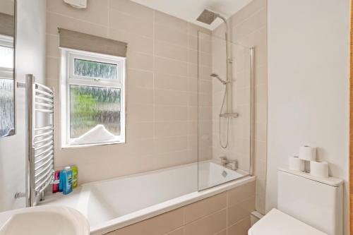 ein Bad mit einer Badewanne, einem WC und einem Fenster in der Unterkunft Livestay-Three Bedroom House in Belvedere with Private Garden in Belvedere