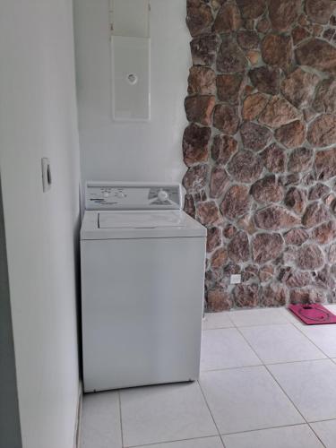 a white refrigerator in a kitchen next to a stone wall at Laure hébergement chambre tiare in Faaa