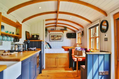 eine Küche mit blauen Schränken und ein Bett in einem Zimmer in der Unterkunft FLORA Luxury Retreat, Private Garden, Views & Hot Tub in Durham
