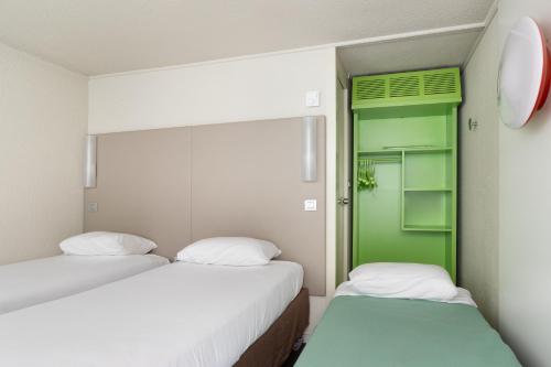 2 camas en una habitación con puerta verde en Campanile Morangis Orly en Morangis