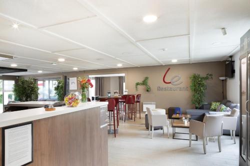 a restaurant with a bar and tables and chairs at Hotel Morangis Orly in Morangis