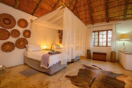 um quarto com uma cama de dossel num quarto com tectos em madeira em South Safari Lodge em Marloth Park