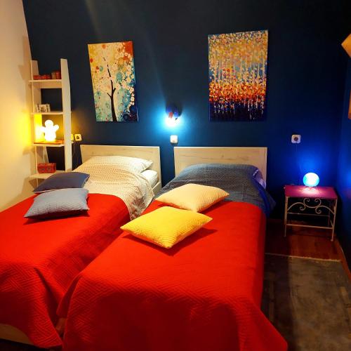 a bedroom with two beds with red sheets and blue walls at Holiday house "LEA" in Lukoran