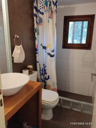 y baño con aseo, lavamanos y cortina de ducha. en Cabaña UMA - Rumi Huasi en Mar del Plata