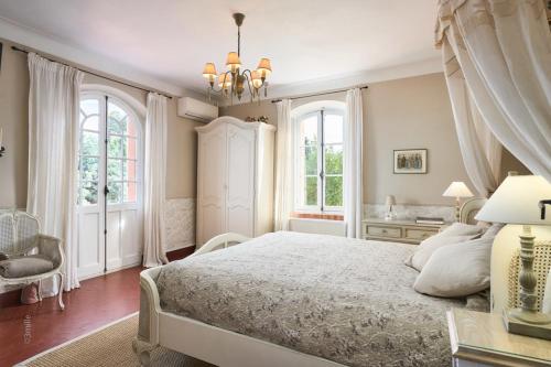 une chambre avec un grand lit et deux fenêtres dans l'établissement Bastide Les Cigales, à Antibes