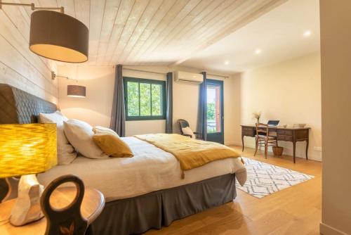 een slaapkamer met een groot bed, een bureau en een tafel bij La Longère Bordeaux gite de charme prés de Bordeaux in Cénac