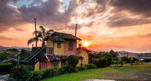 a house on a hill with the sunset in the background at Capricho Asturiano in Santo Antônio do Leite