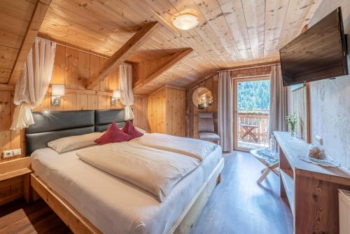 ein Schlafzimmer mit einem großen Bett in einem Holzzimmer in der Unterkunft Der Ortnerhof - Hotel & Reiterhof in Prägraten