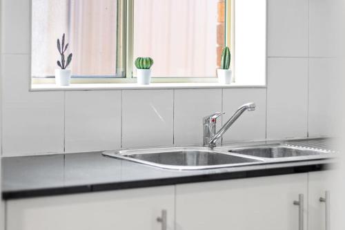 a white kitchen with a sink and two windows at Comfort Queen Room - Private - Prime Spot in Sydney